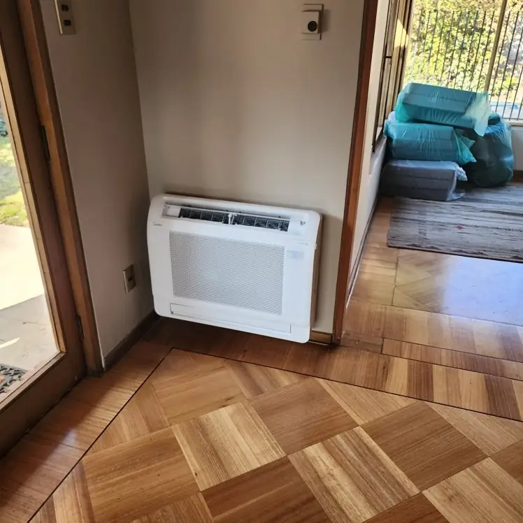 Consola de piso Midea de un multisplit instalada en un living con piso de parquet